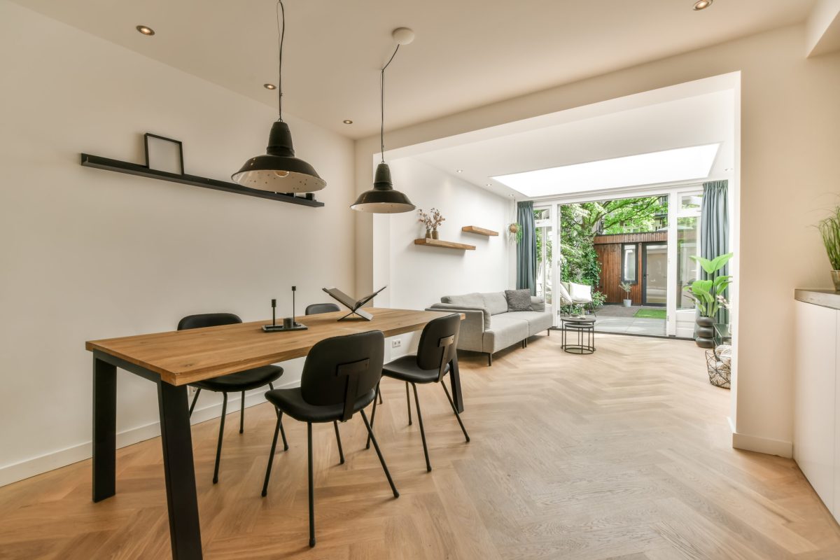 a dining room with wood flooring and white walls, there is a large wooden table surrounded by black chairs
